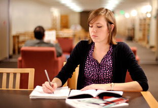 Student writing at a desk