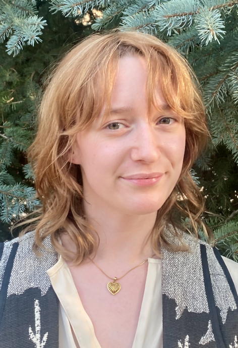 Portrait of Kaylee Fessler in front of a spruce tree.