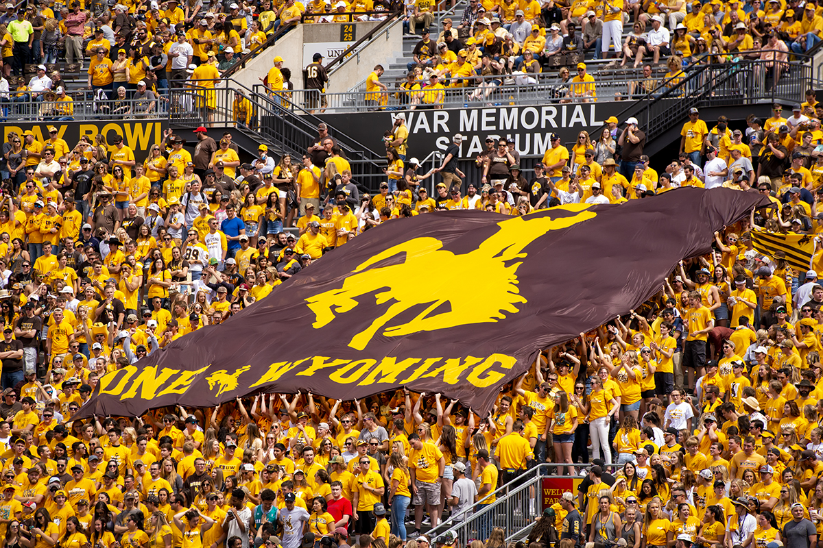 fans at UW football game hold a large group flag