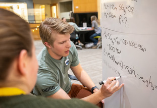 UW students work together, using a whiteboard, at the STEP Tutoring Center.