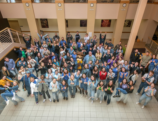 An aerial view of a large group of students posing with Pistol Pete in the downstairs area of the Union Building