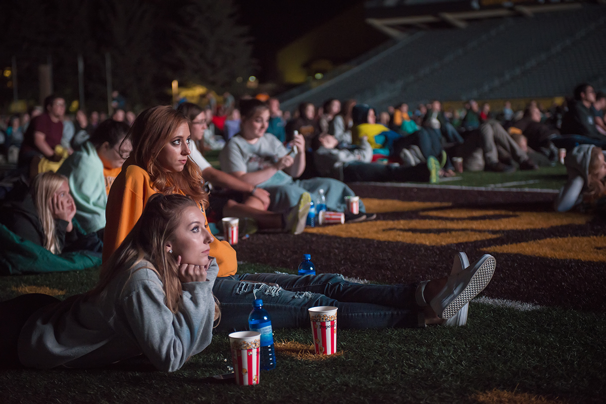 Students watch a movie in the football stadium