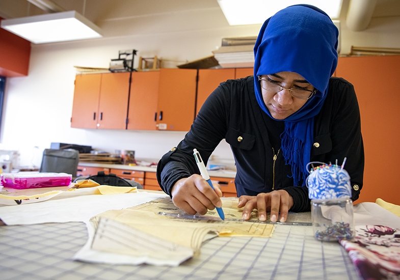 a family and consumer sciences graduate student in the design merchandising and textiles masters program measures a pattern to sew