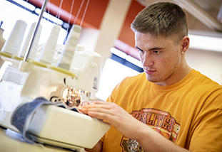 a family and consumer sciences student at a sewing machine in the sewing lab