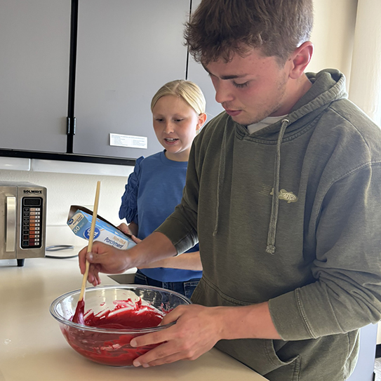 two family and consumer sciences students making a red velvet cake batter