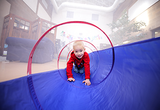 a child crawling through a plastic tunnel representing human development and family science in the department of family and consumer sciences