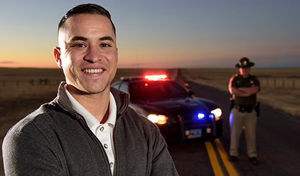 student poses in front of highway patrol officer and vehicle