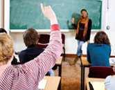 students raise hands in a classroom to get the attention of the teacher