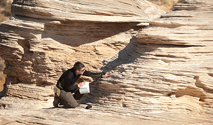 student does geology field work in front of rock formation