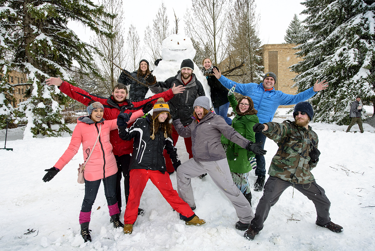 students pose in front of a giant snowman they made