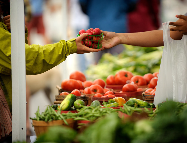 Person handing tomatoes to another person
