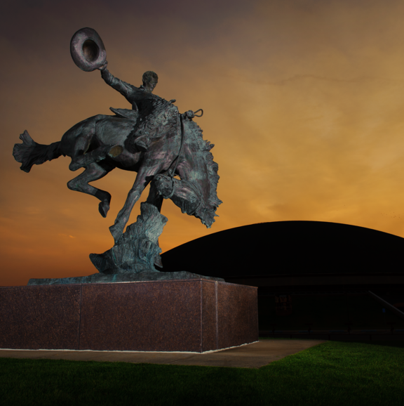 bucking horse and rider statue in front of arena auditorium