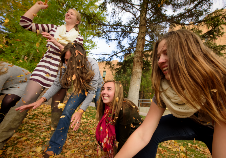 students playing in fall leaves