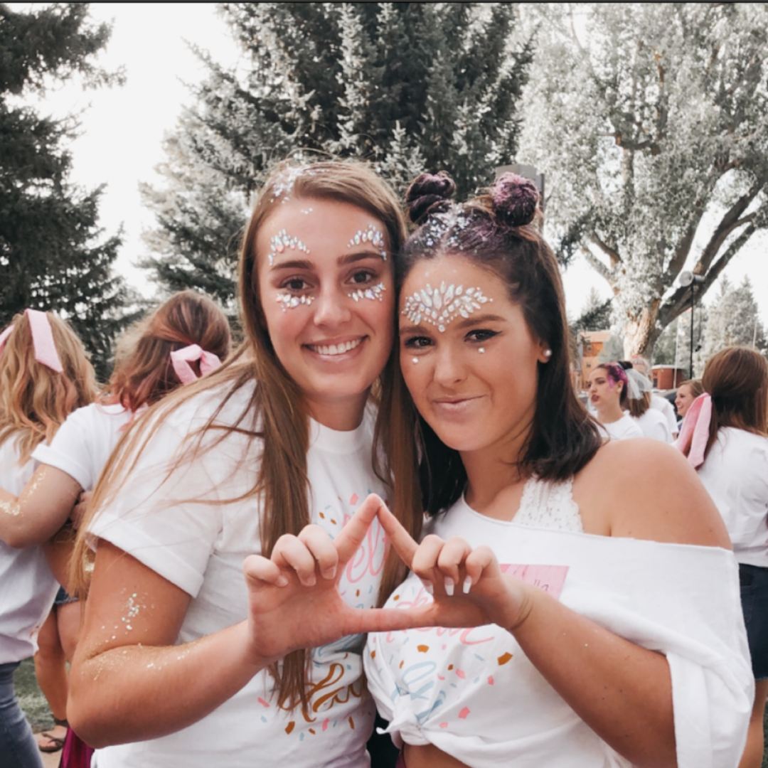 sisters holding the tri delta logo