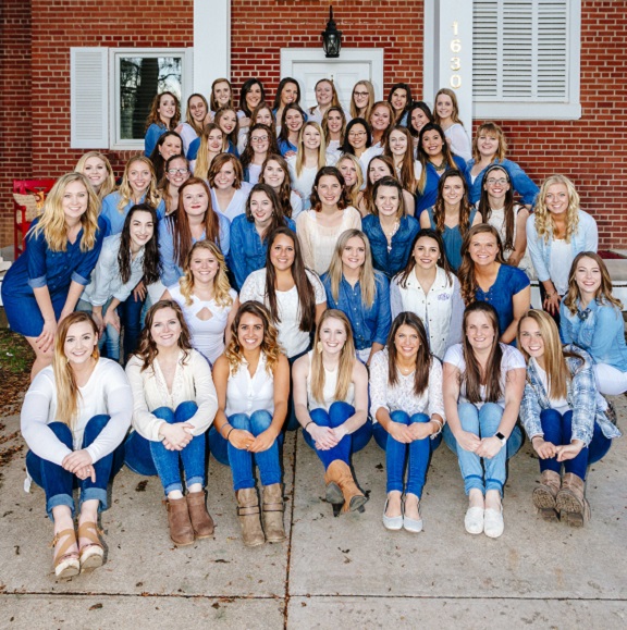 Photo of the entire chapter in front of the house, everyone is wearing white and denim