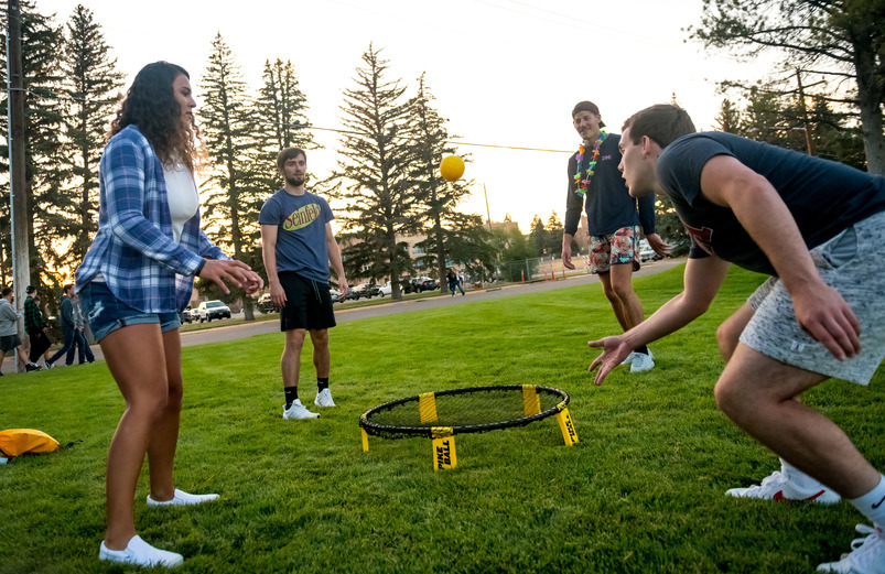 People play an outdoor lawn game, spikeball, during an event