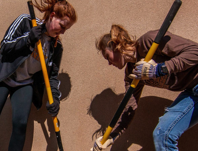 Two students with shovels volunteering
