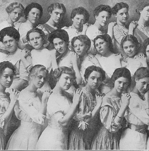 21 girls leaning on each other for a group photo. In black and white. 