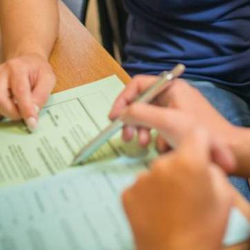 close up of hand holding pen assisting a student with paperwork