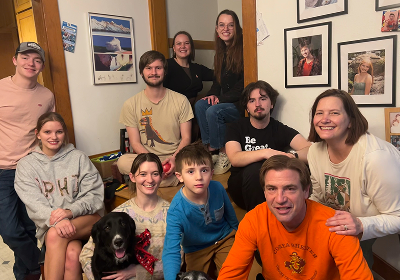 eight adults and a child and two dogs pose on the steps after Christmas dinner