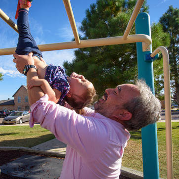 A father plays with his child at the playground of the University Apartments