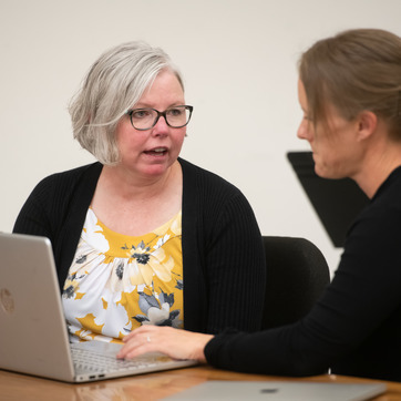 Teacher interacting with student in front of laptop