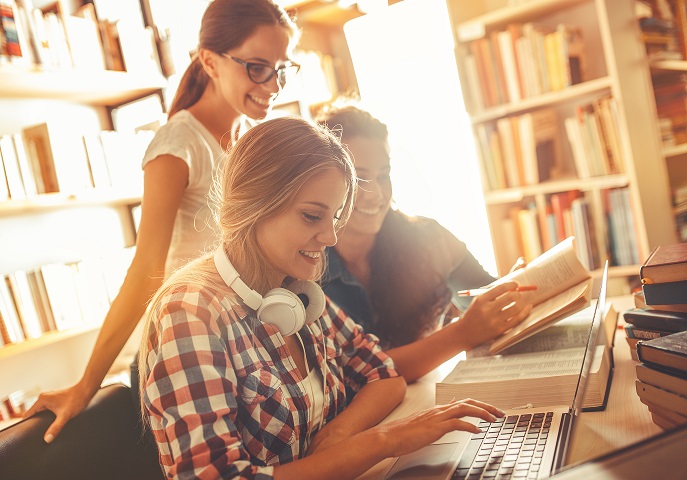 A group of three students studying together in a library