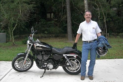 Mark Shuster, standing by motorcycle.