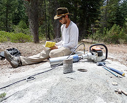 man taking drill core samples of bedrock