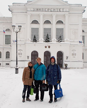 Three people in front of building with snow