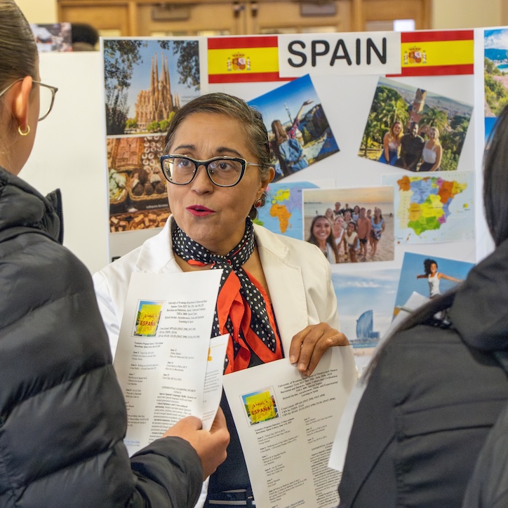 Faculty member talking to two students in front of poster