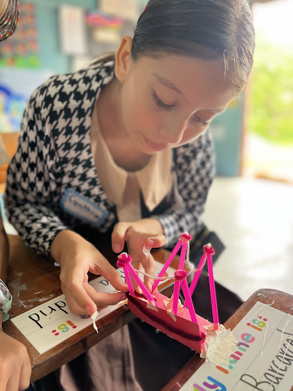 Young student in Belize classroom working on a building crafts project