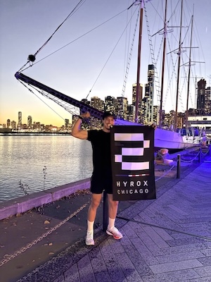 Hamza standing at a pier in Chicago with a flag