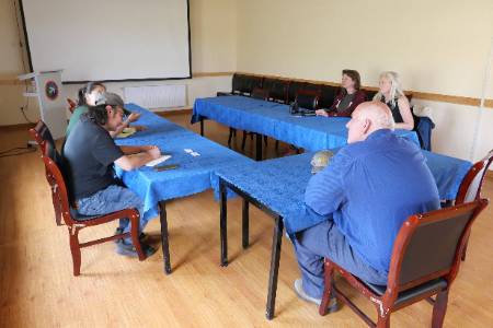 John leading a discussion with Isa and three others at a blue table