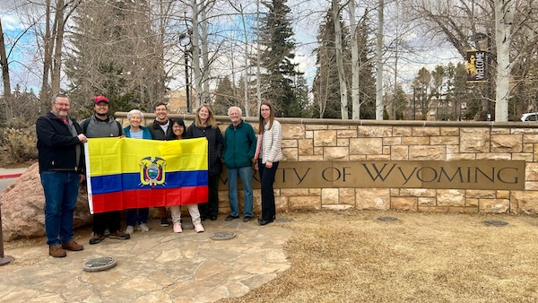 Eight people in front of UW sign with the Ecuador flag