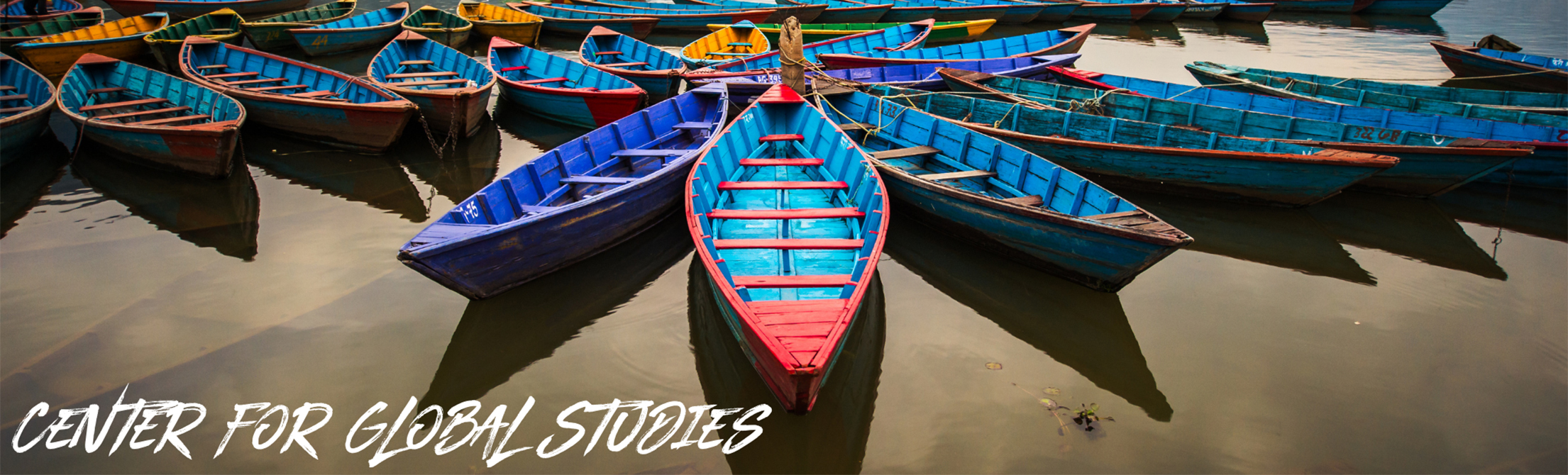 A line of blue and other multicolored boats sitting in water, with a caption that reads "Center for Global Studies."