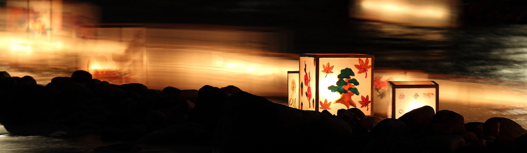 Paper lantern on a river at night by Greg Ronco