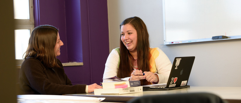 Advisor and student sitting at desk with laptop