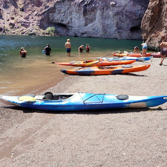 kayaks on a beach and people sitting in the water