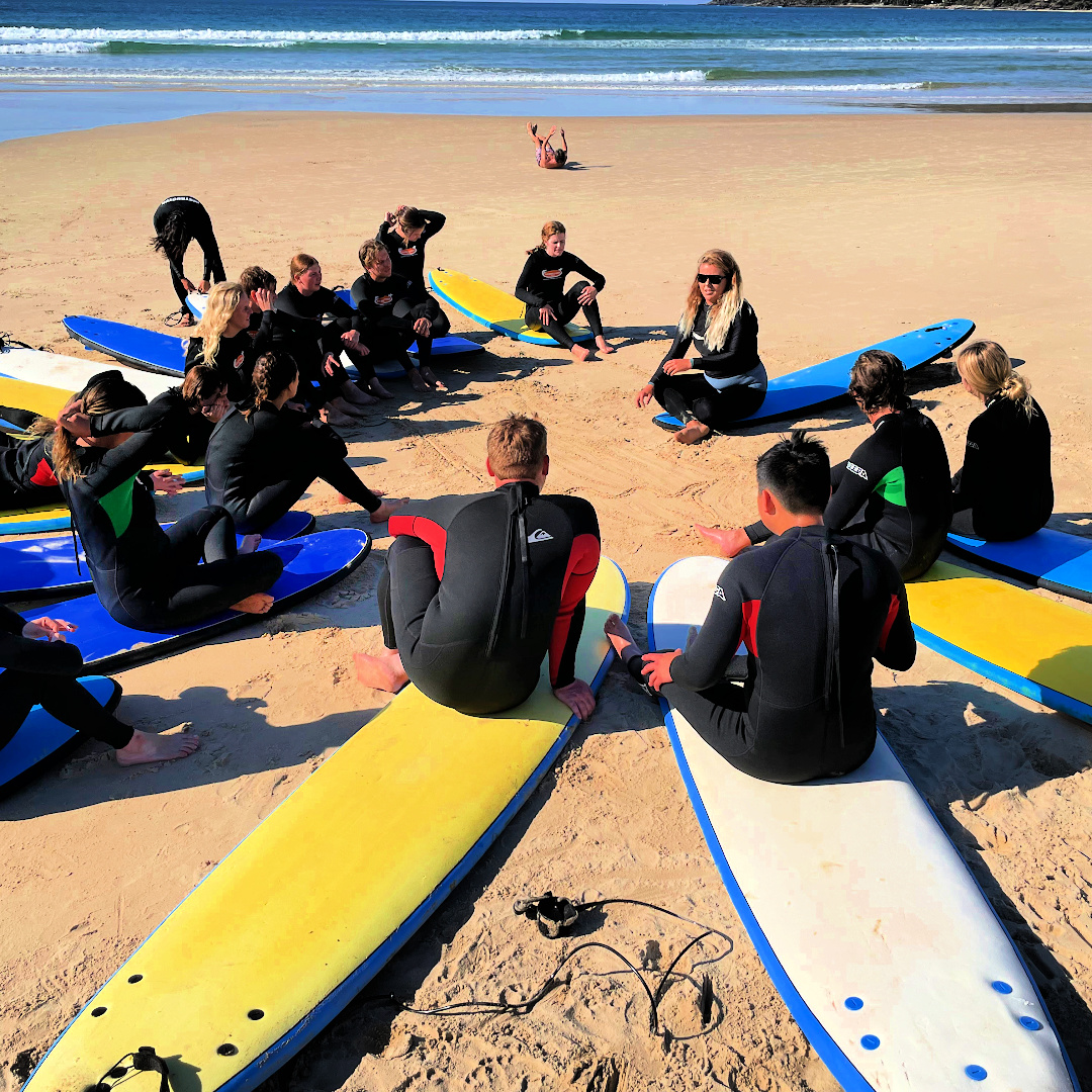 students sitting on surfboard listening to instructor