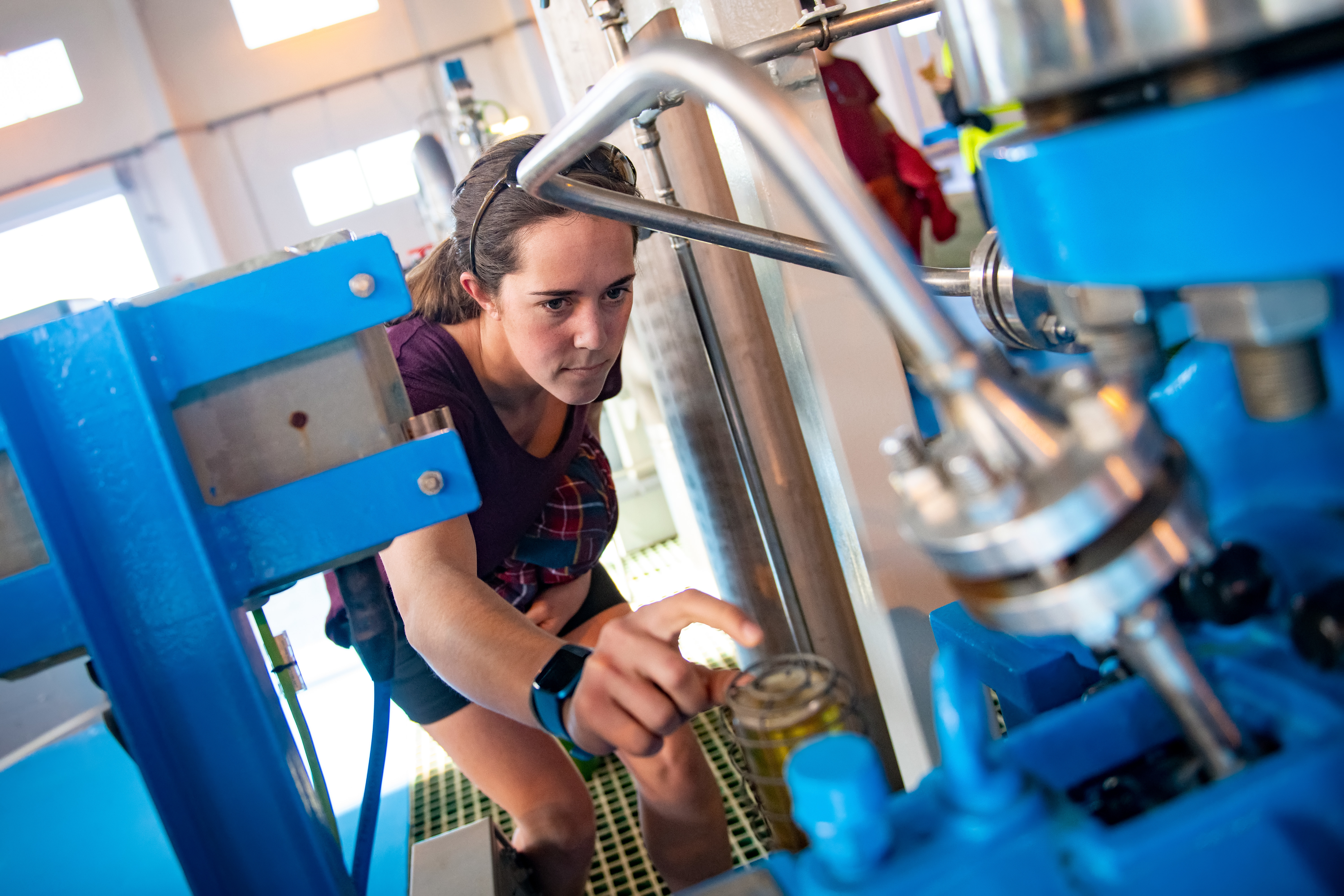 A student looking in a large piece of machinery