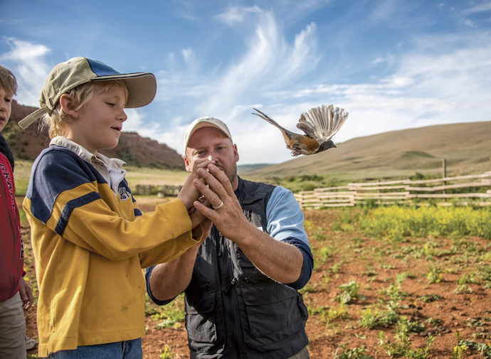 A man helps a boy release a bird at an event