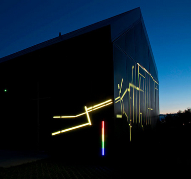 Photo of building or shed with colored lights shining on the sides.