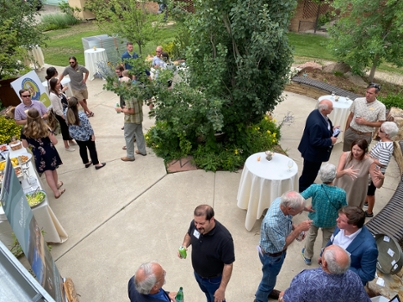 Overhead photo of attendees mingling on the patio of the Bergman Gardens behind the Bim Kendall House at the reception for the tree dedication. 