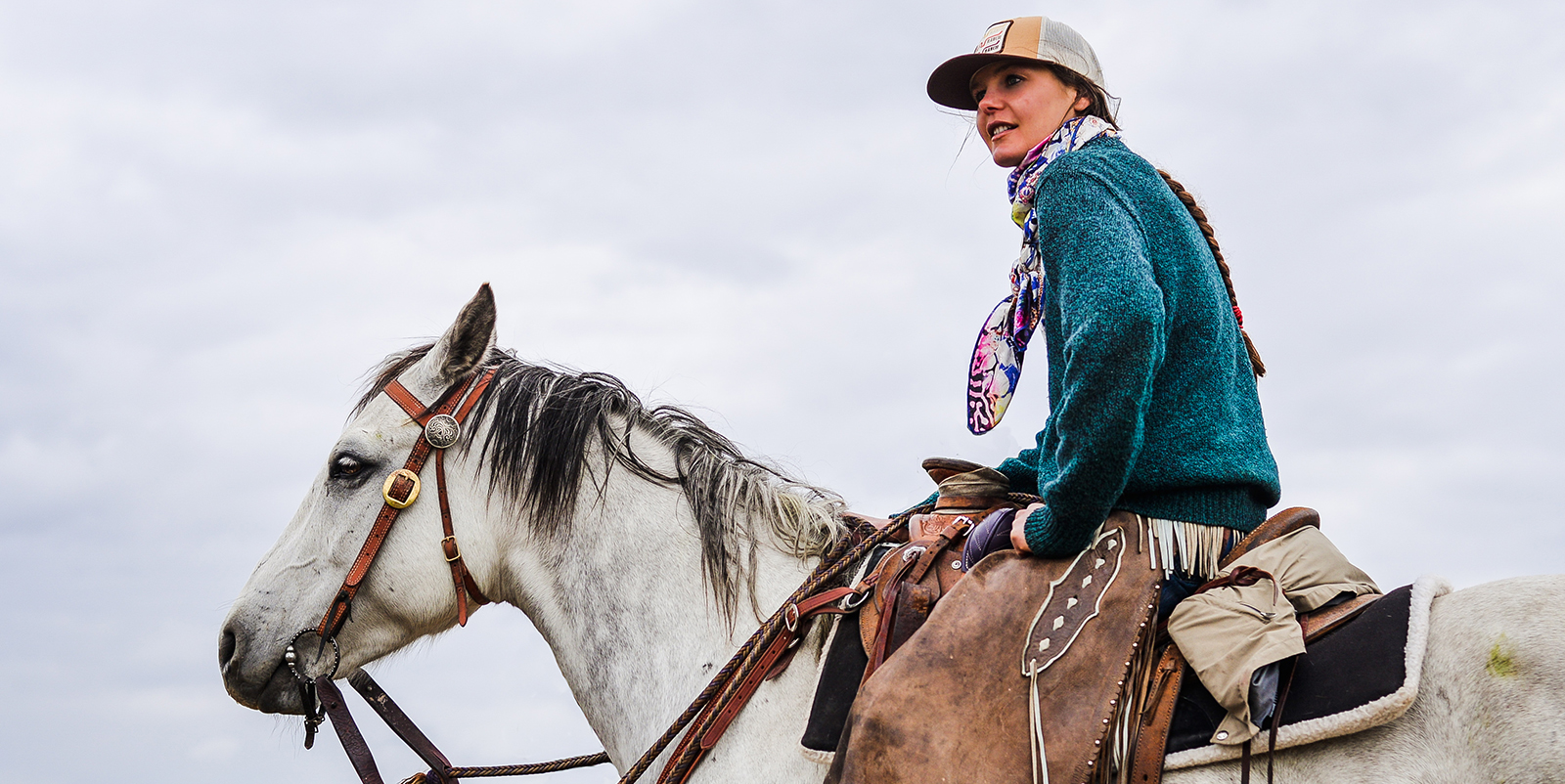 A woman on horseback wearing chaps