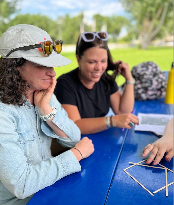 Two women look at a puzzle on a table