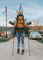 Person wearing a deer costume and a backpack with skis on it
