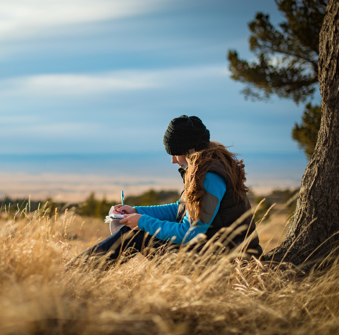 A woman journaling in a meadow