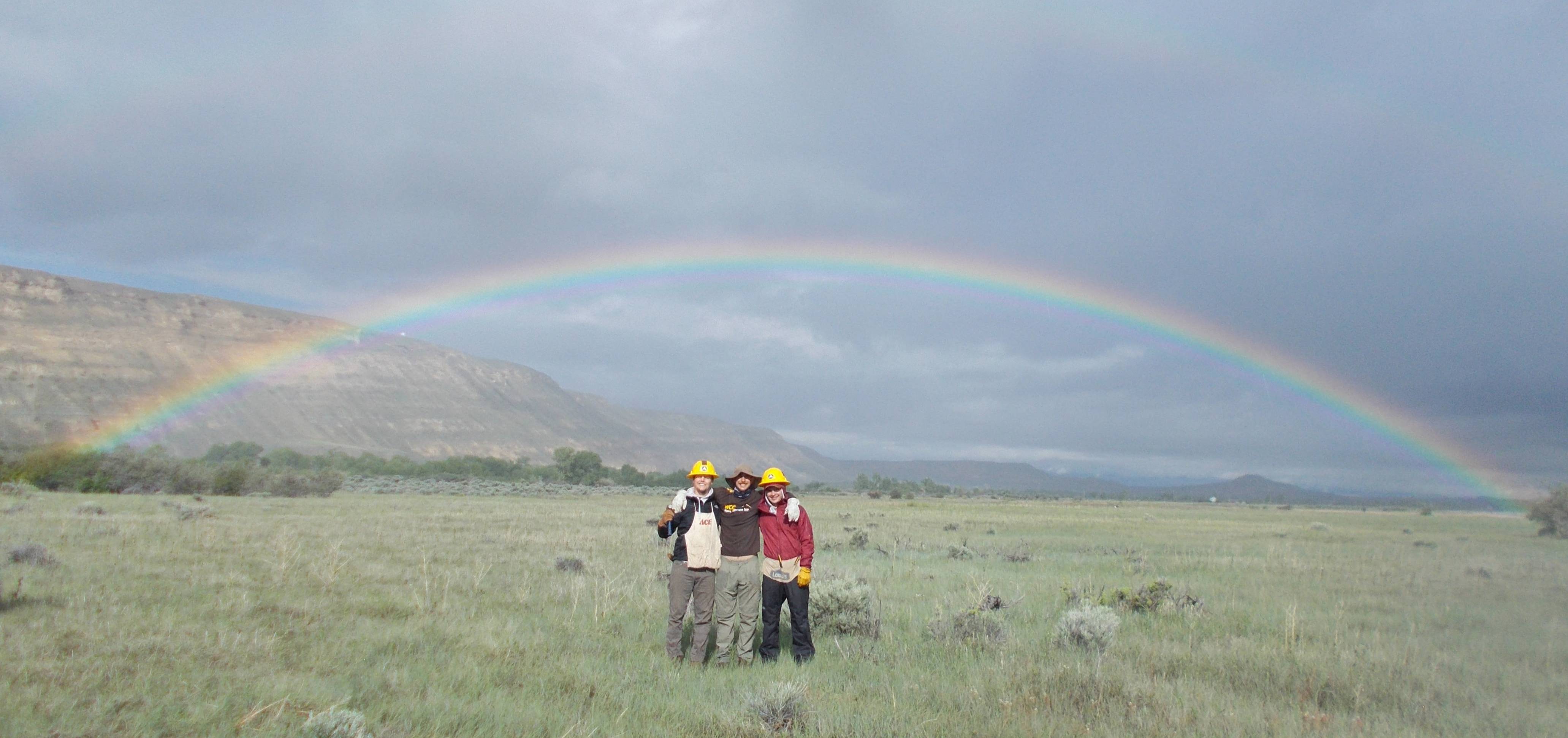 Crew members stand under a rainbow