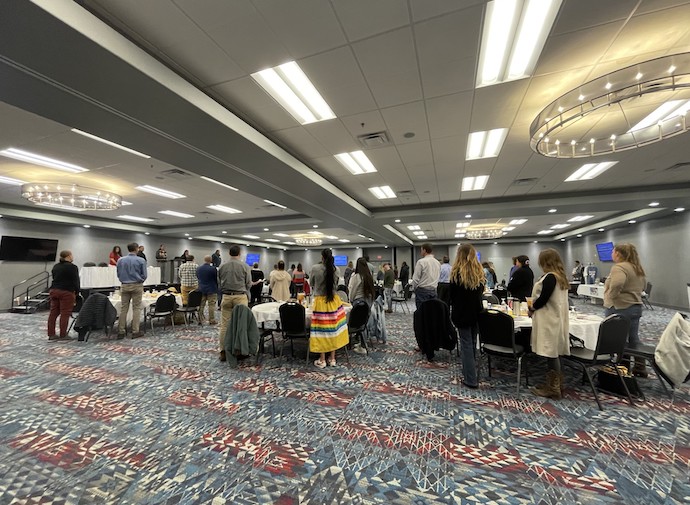 Participants at a tourism summit stand around tables